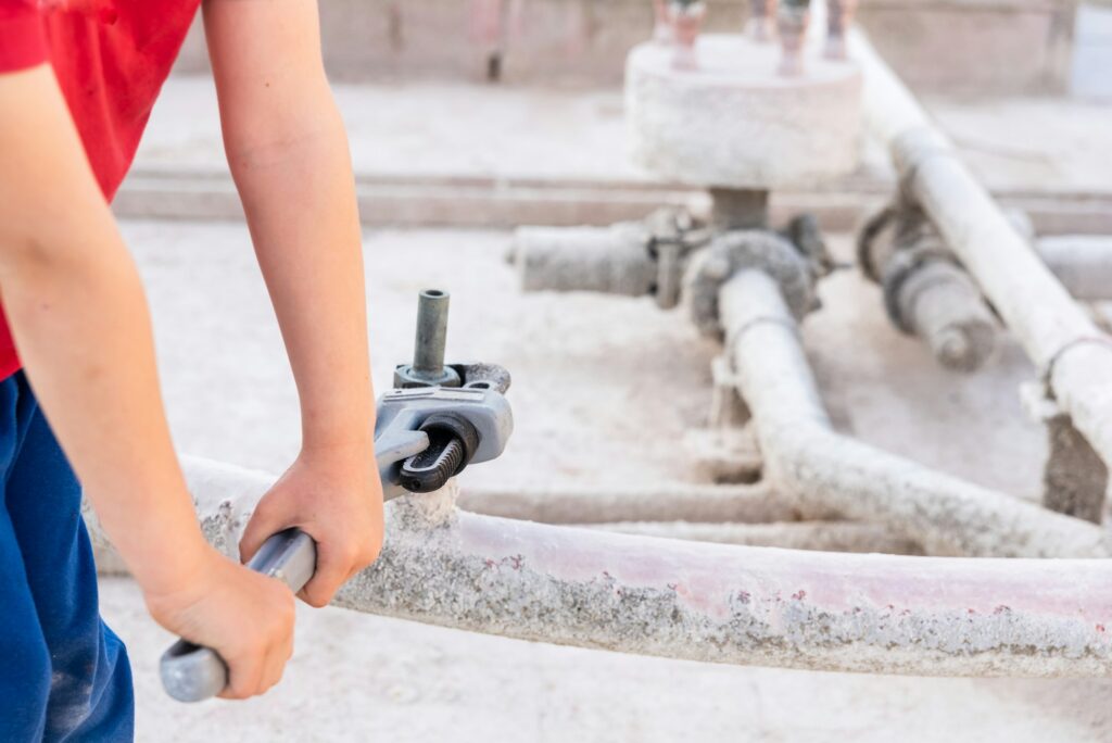 Children using a heavy-duty straight pipe plumbing wrench to repair a pipe.