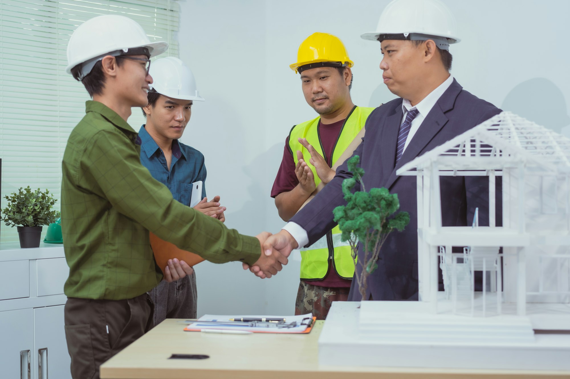 In the office,home builders build homes clients to discuss plans designs stand tables,hold hands