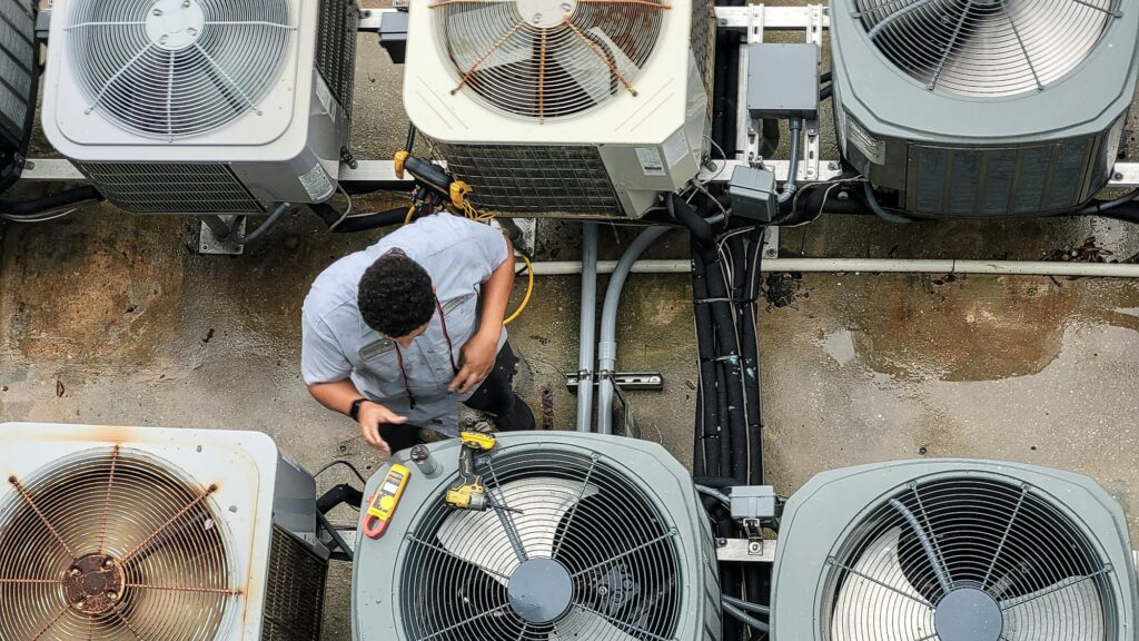 Young HVAC technician using modern technology to work on and maintain outdoor HVAC units at condo.